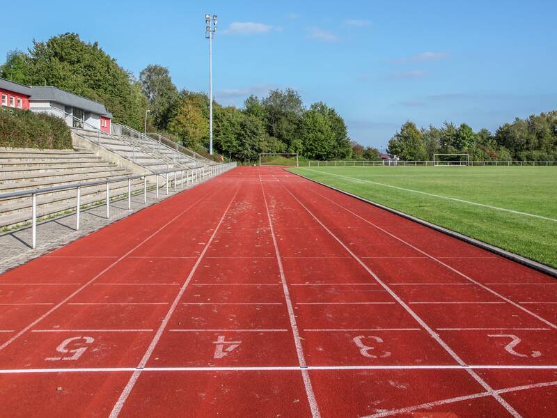 Die rote Tartanbahn im Haldenberg-Stadion, rechts davon der Rasen und links die Tribüne.