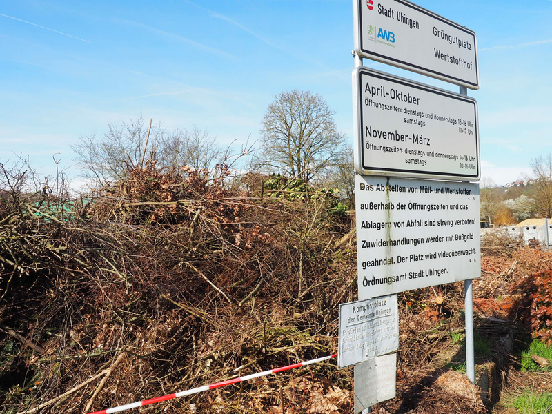 Auf dem asphaltierten Platz der Grüngutsammelstelle liegt ein großer Berg aus Ästen, Zweigen und anderen pflanzlichen Teilen.