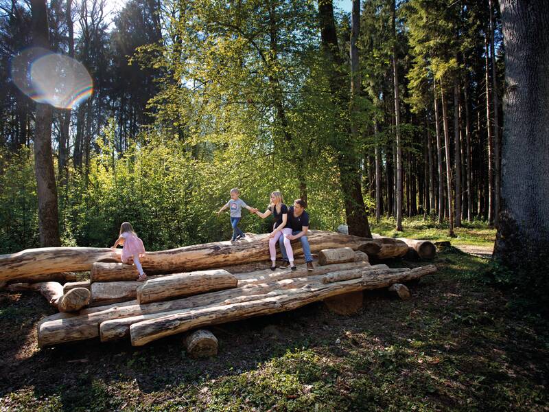 Eine Familie im Landschaftspark Schloss Filseck auf Baumstämmen, die bewusst zum Entspannen aufgestellt wurden. 