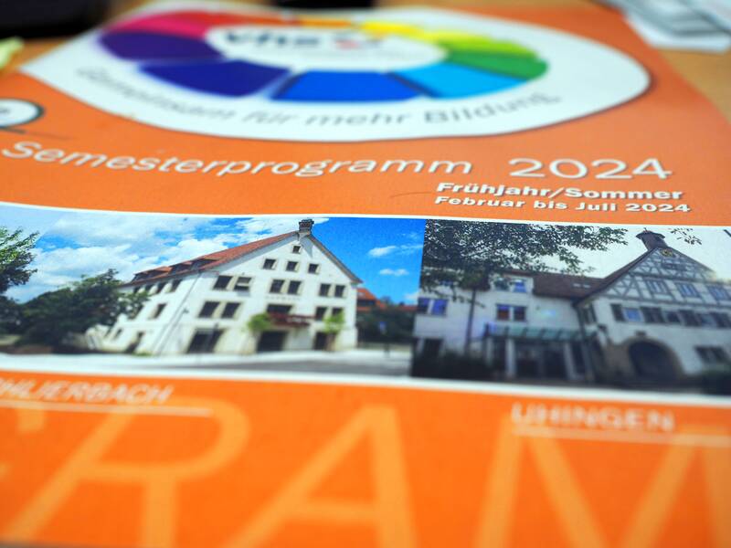 Das Programm der Volkshochhochschule auf orangenem Hintergrund.