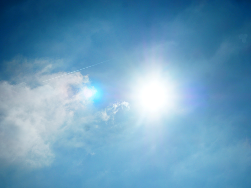 Am blauen Himmel ziehen Schleierwolken an der strahlenden Sonne vorbei.