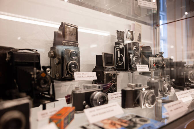 In einer beleuchteten Vitrine stehen mehrere Fotoapparate, die den Wandel der analogen Fotografie nachempfinden sollen.