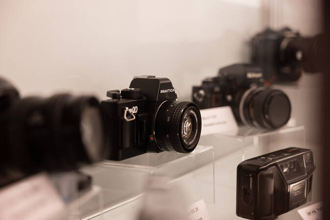 In einer beleuchteten Vitrine stehen mehrere Fotoapparate, die den Wandel der analogen Fotografie nachempfinden sollen.