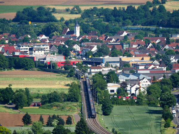 Uhingen im Sommer, Gebäude und Bäume sowie ein Zug auf einem Gleis