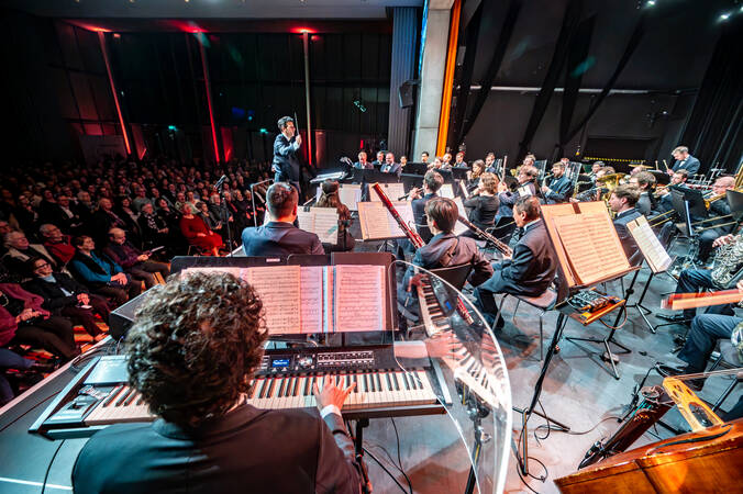 Ein Orchester auf der beleuchteten Bühne und davor das Publikum.