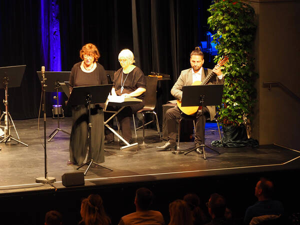Drei Musiker, im Vordergrund singt eine braunhaarige Dame und rechts von ihr sitzen eine Keyboard-Spielerin und ein Gitarrist.