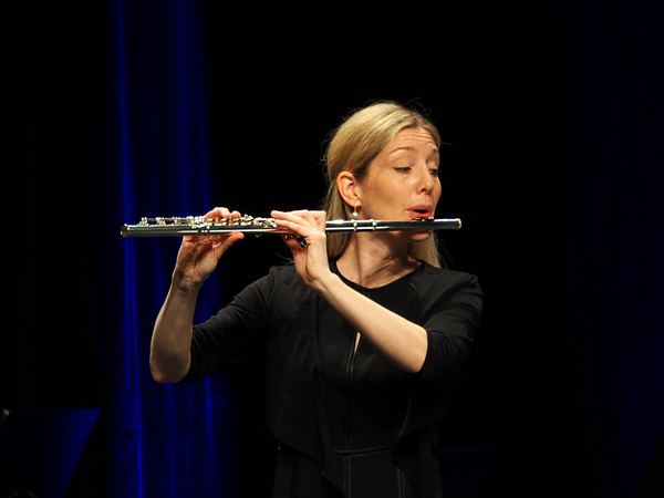 Eine blonde Frau spielt auf der Querflöte.