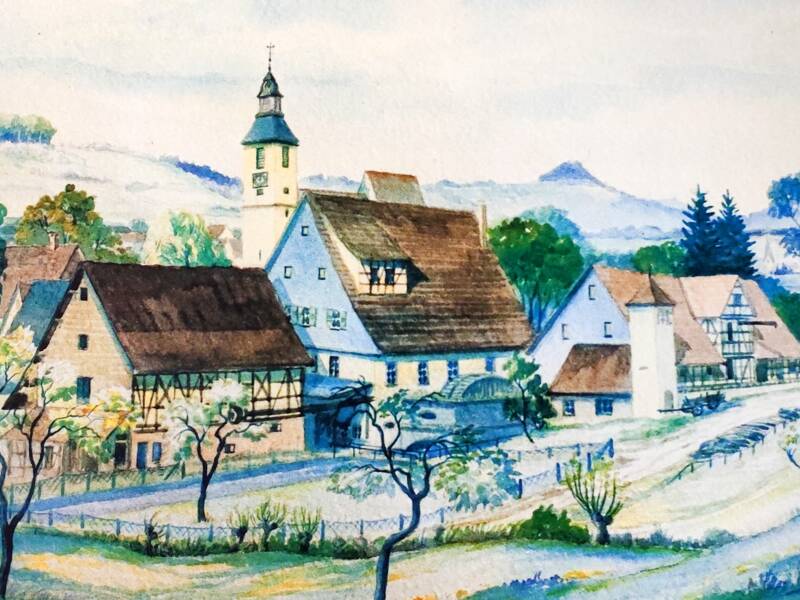 Eine undatierte Aquarell-Zeichnung zeigt alter Fachwerkgebäude, um Teil mit Mühlrad, eine kleine Kirche mit Turm und im Hintergrund einen großen Kirchturm mit Kreuz und Uhr. Vor den Häusern sind eingezäunte Gärten und vereinzelte Bäume auf den Wiesen.