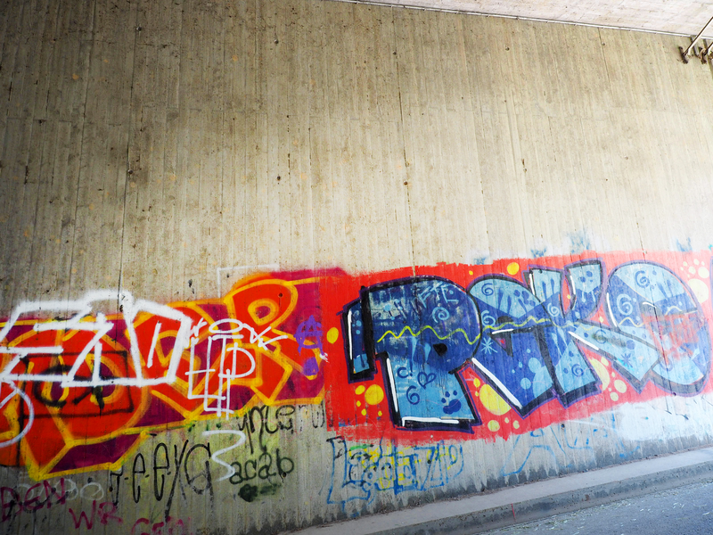 Ein mit Spraydose aufgesprühter bunter Schriftzug, ein Graffito, auf der legalen Graffiti-Wand.