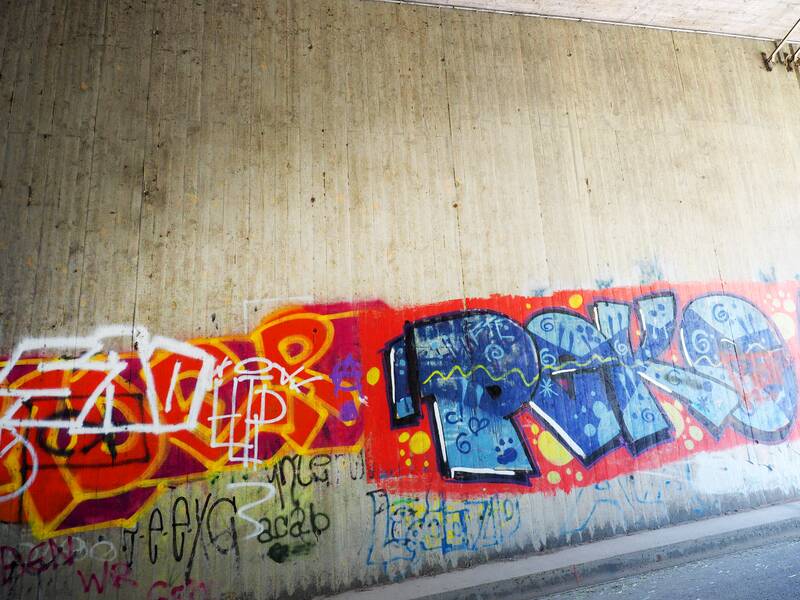 Ein mit Spraydose aufgesprühter bunter Schriftzug, ein Graffito, auf der legalen Graffiti-Wand.