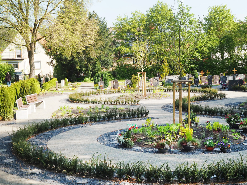 Auf dem Uhinger Friedhof gibt es eine Urnengrabanlage: Die Urnen befinden sich an einem geschwungenen Weg, dazwischen sind Bäume gepflanzt.