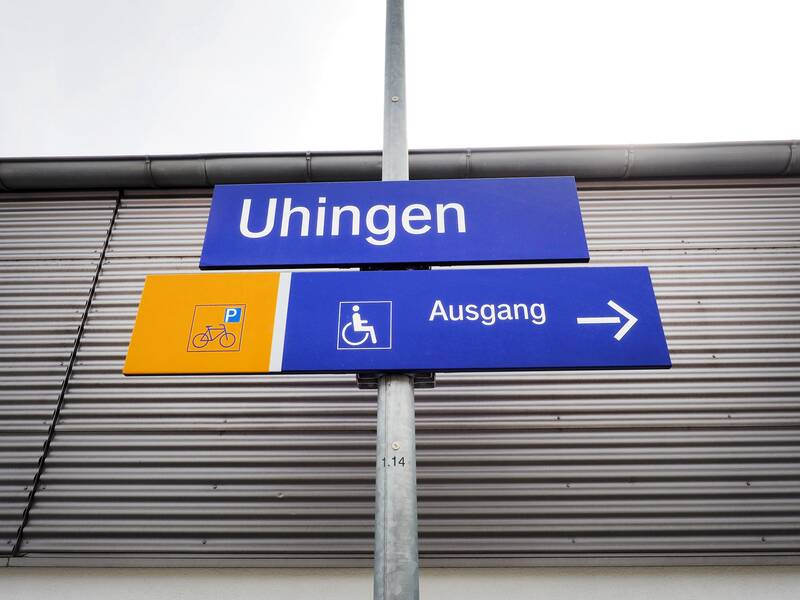 Am Uhinger Bahnof hängen Schilder, auf denen mit weißer Schrift auf blauem Grund "Uhingen" und "Ausgang" stehen.