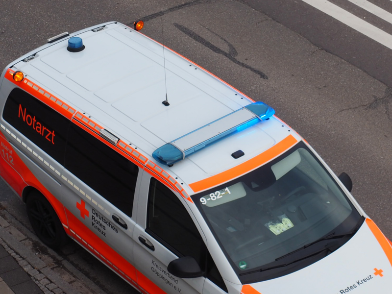 Ein Rettungsfahrzeug des Deutschen Roten Kreuzes steht auf einer Straße und ist von Oben zu sehen. Das Blaulicht leuchtet.