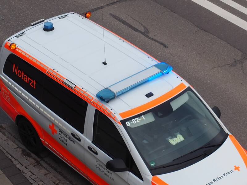 Ein Rettungsfahrzeug des Deutschen Roten Kreuzes steht auf einer Straße und ist von Oben zu sehen. Das Blaulicht leuchtet.