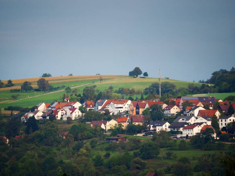 Eine Ortsansicht auf Diegelsberg, eingebettet in Felder, Wiesen, Wald und auf einem Hügel.