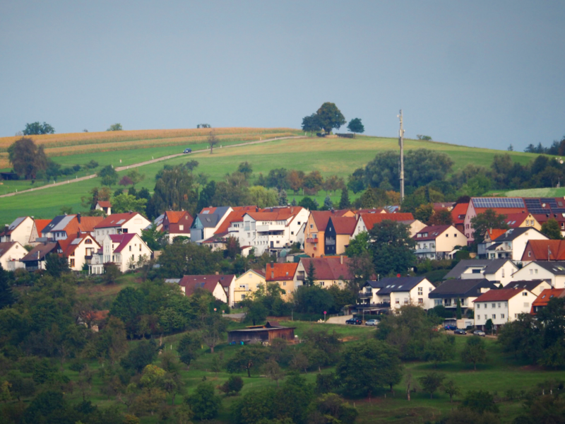 Eine Ortsansicht auf Diegelsberg, eingebettet in Felder, Wiesen, Wald und auf einem Hügel.