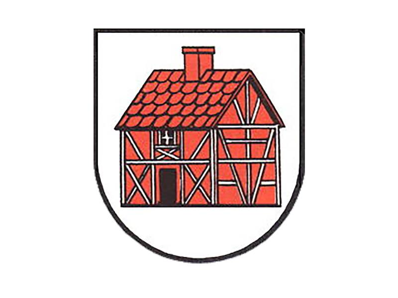 Das Wappen des Stadtteils Holzhausen ist wie ein Schild, das unten abgerundet ist. Darauf ist auf weißen Grund ein rotes Fachwerkhaus  mit weißen Balken, schwarzem Türeingang, darüber einem weißen Fensterkreuz und auf dem Dach mit roten Ziegeln und rotem Schornstein. 