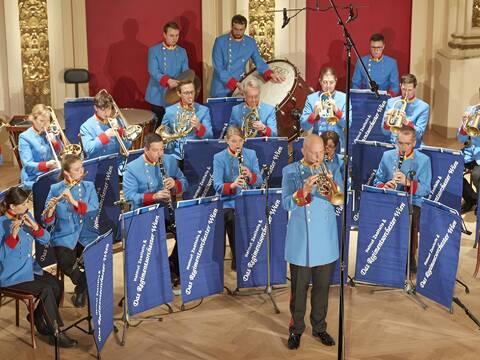 Ein Orchester bestehend aus Frauen und Männer die alle ein Blechblasinstrument spielen.