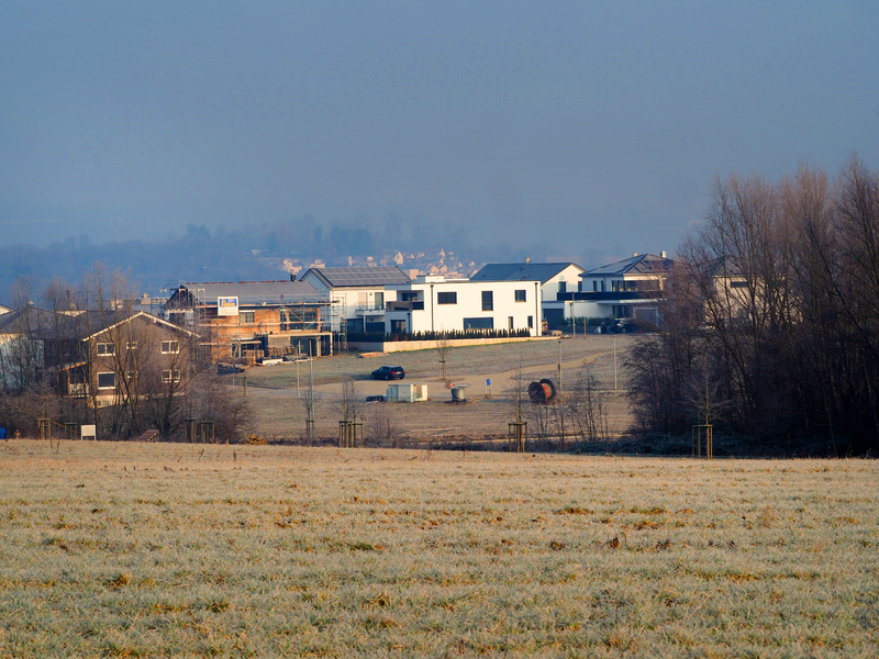 In einem Neubaugebiet steht ein Rohbau eines Hauses mit Gerüsten. Daneben stehen neue Häuser.