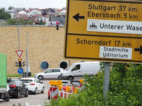 An einer Kreuzung stehen an einer roten Ampel mehrere Fahrzeuge. Rechts davon ist ein großes Verkehrsschild mit den Fahrtrichtungen Stuttgart/Ebersbach und Schorndorf.