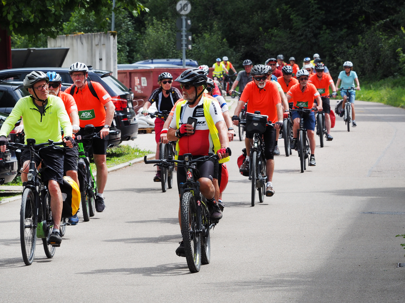 Mehrere Frauen und Männer fahren auf einer Straße Fahrrad.