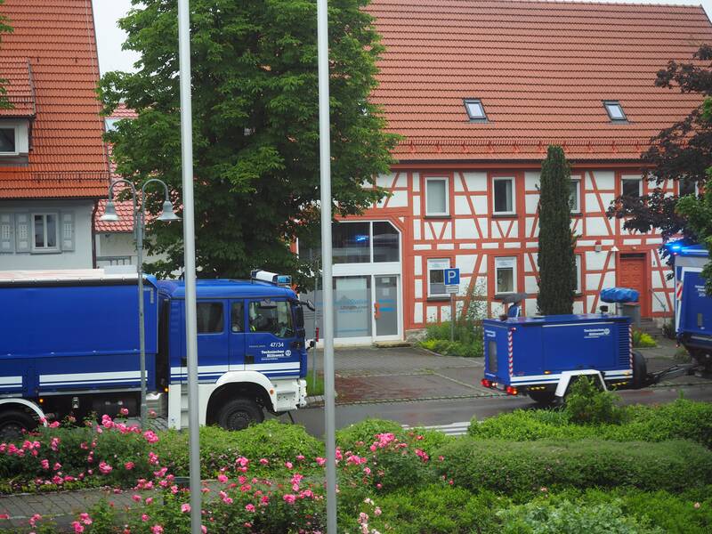 Zwei blaue THW-Fahrzeuge stehen auf einer Straße vor einem Fachwerkhaus.