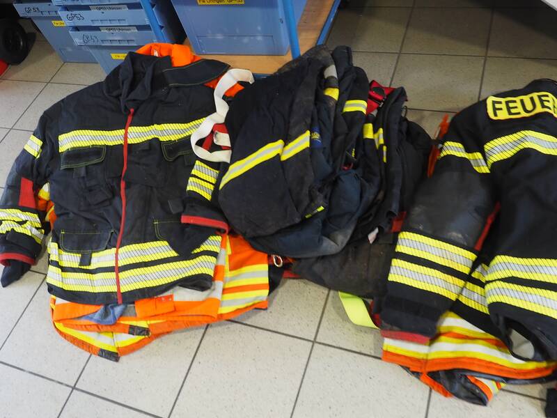 Benutzte Einsatzjacken der Freiwilligen Feuerwehr liegen auf dem Boden.