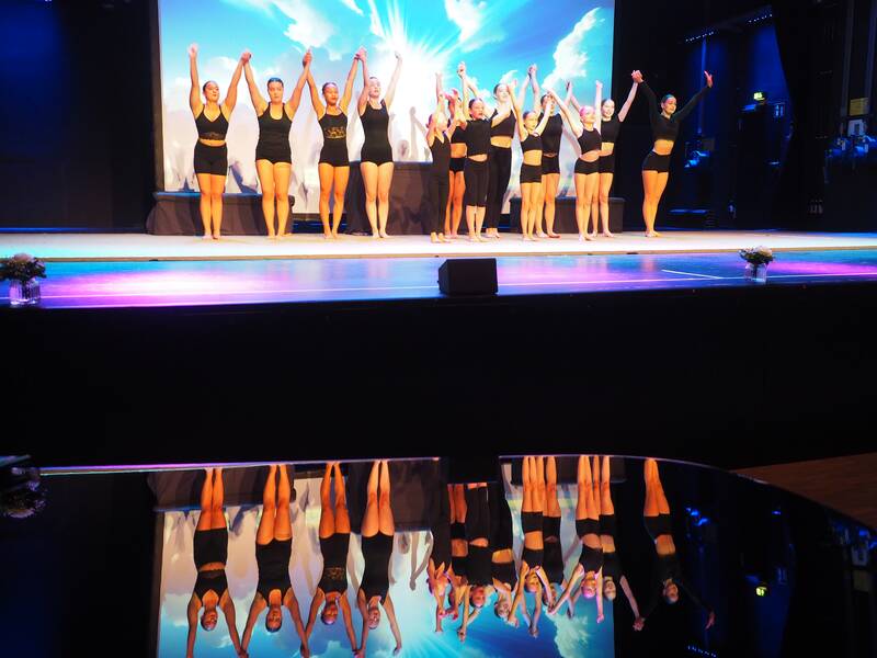 In schwarz gekleidete Sportakrobatinnen des TV Uhingen wirbeln auf der Bühne des Uditoriums umher.