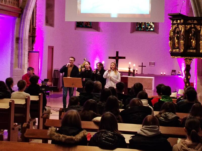 Jugendliche die vor einem Altar stehen und singen.