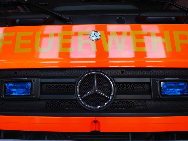 Die Front eines Feuerwehrfahrzeugs von Vorne mit Aufschrift und Blaulicht.