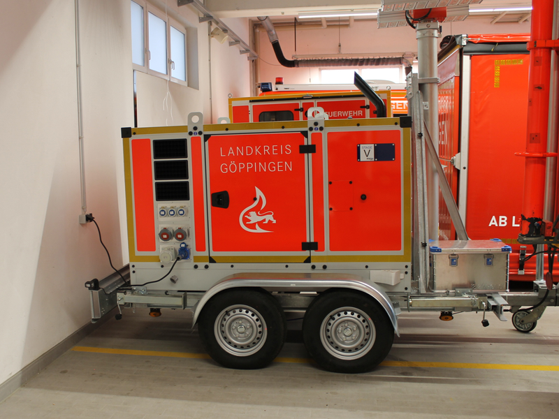 Der Lichtmast-Anhänger in der Fahrzeughalle der Uhinger Feuerwehr hinter einem Fahrzeug.